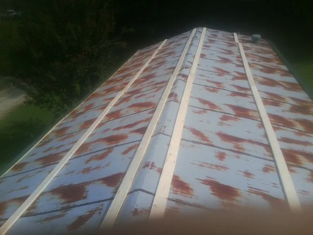 Rusted metal roof panels with new wood purlins before replacement — Storm Damage Roof Repair in Brook Park by Roofing Brothers