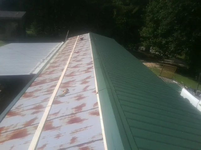 Old rusted panels beside newly installed green metal roofing — Wind Damage Roof Repair by Roofing Brothers in Brook Park