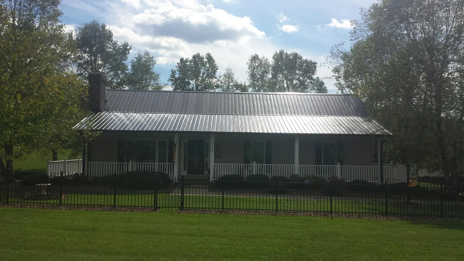Gray metal roof on a brick ranch with a full width front porch — Gutter Guard Installation work by our crew in Brook Park